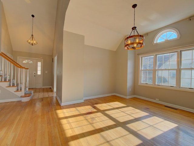 foyer entrance featuring light hardwood / wood-style floors, lofted ceiling, and a notable chandelier