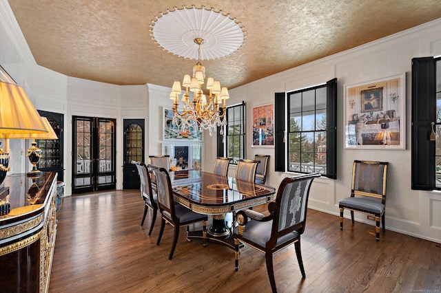 dining space with crown molding, an inviting chandelier, dark hardwood / wood-style floors, a textured ceiling, and french doors