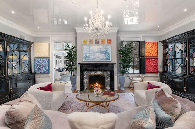 living room with an inviting chandelier, crown molding, a fireplace, and wood-type flooring