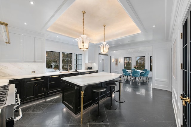 kitchen featuring a kitchen breakfast bar, a tray ceiling, decorative light fixtures, and a kitchen island