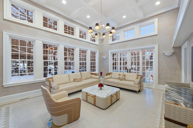 living room with beam ceiling, a high ceiling, coffered ceiling, a notable chandelier, and french doors