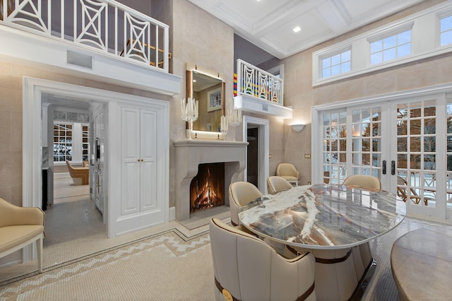 dining space with french doors, coffered ceiling, a large fireplace, beam ceiling, and a high ceiling