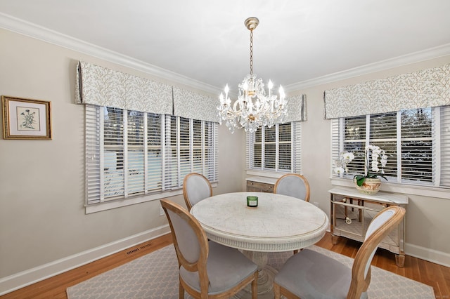 dining room featuring hardwood / wood-style flooring, crown molding, and an inviting chandelier