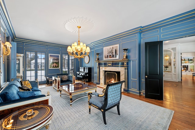 living area with an inviting chandelier, a high end fireplace, ornamental molding, and a decorative wall
