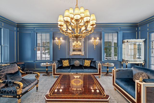 living area featuring carpet, a decorative wall, a chandelier, and a healthy amount of sunlight