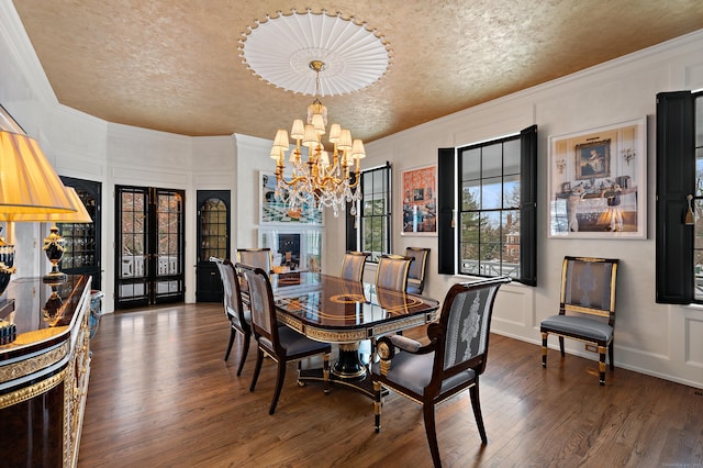 dining area featuring wood finished floors, ornamental molding, a textured ceiling, and a notable chandelier