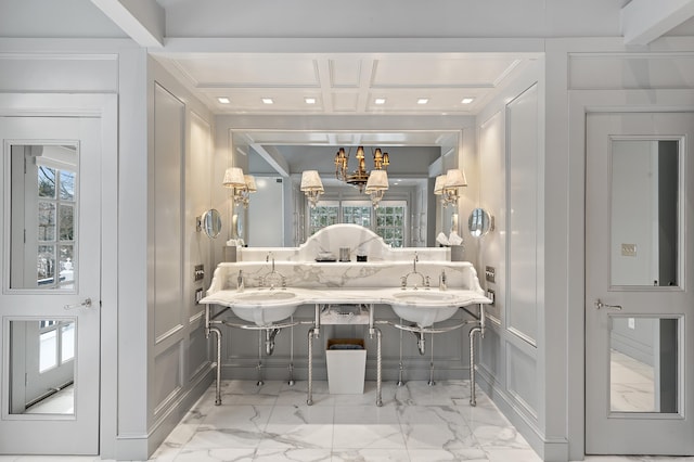 bathroom featuring an inviting chandelier, a decorative wall, marble finish floor, ornamental molding, and coffered ceiling