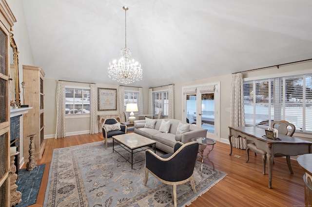 living room with baseboards, vaulted ceiling, wood finished floors, and a notable chandelier