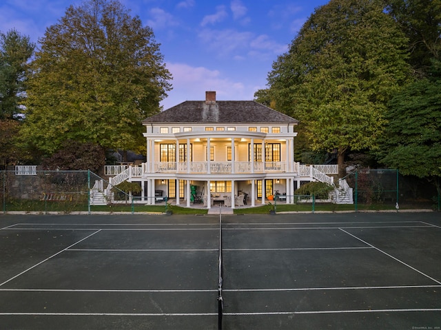 view of sport court featuring stairs, fence, and a wooden deck