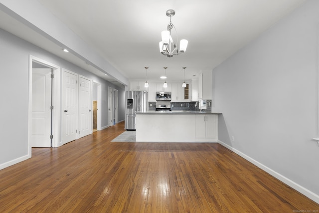 kitchen featuring white cabinetry, kitchen peninsula, stainless steel appliances, a chandelier, and pendant lighting