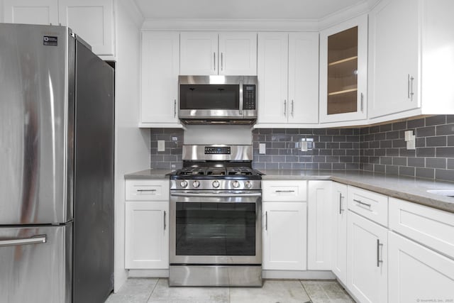 kitchen with backsplash, light tile patterned flooring, white cabinetry, light stone countertops, and appliances with stainless steel finishes