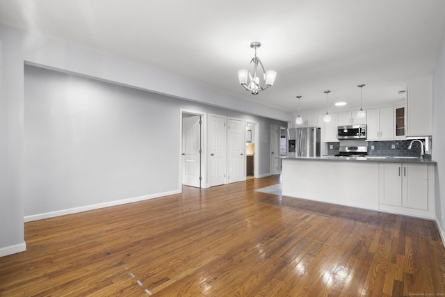 interior space featuring white cabinetry, stainless steel appliances, tasteful backsplash, hanging light fixtures, and a chandelier