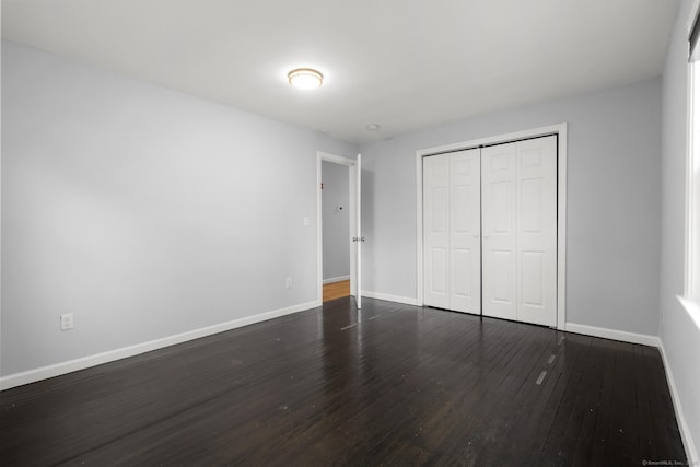 unfurnished bedroom featuring a closet and dark hardwood / wood-style flooring