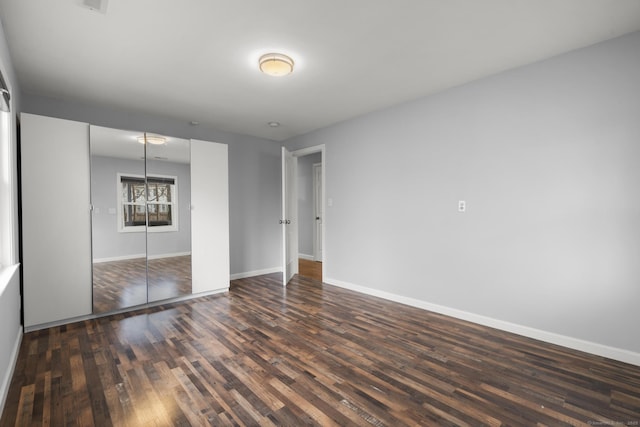 unfurnished bedroom with a closet and dark wood-type flooring