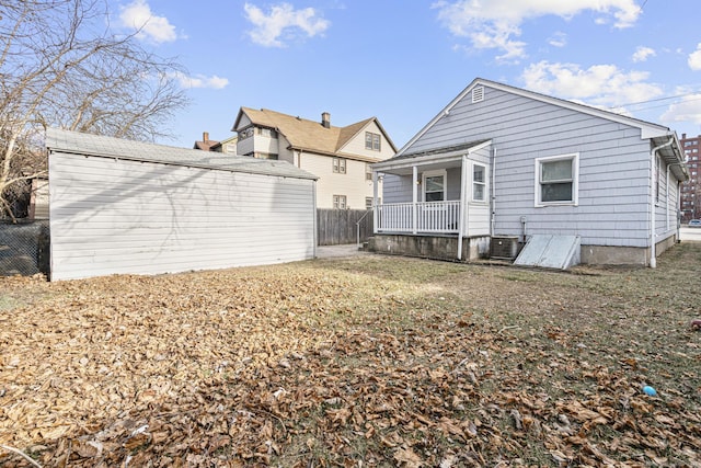 back of property with a lawn, a porch, and central AC