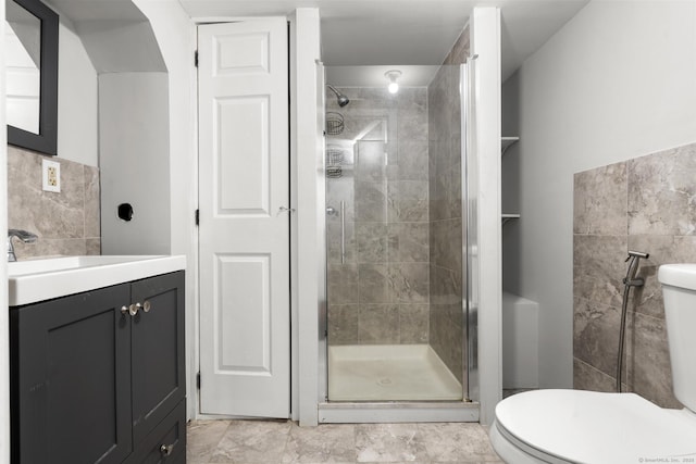 bathroom featuring toilet, vanity, and a shower with door