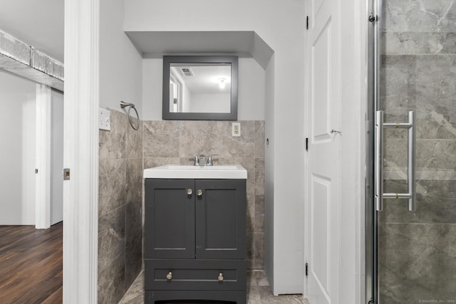 bathroom with vanity, tile walls, and a shower with door