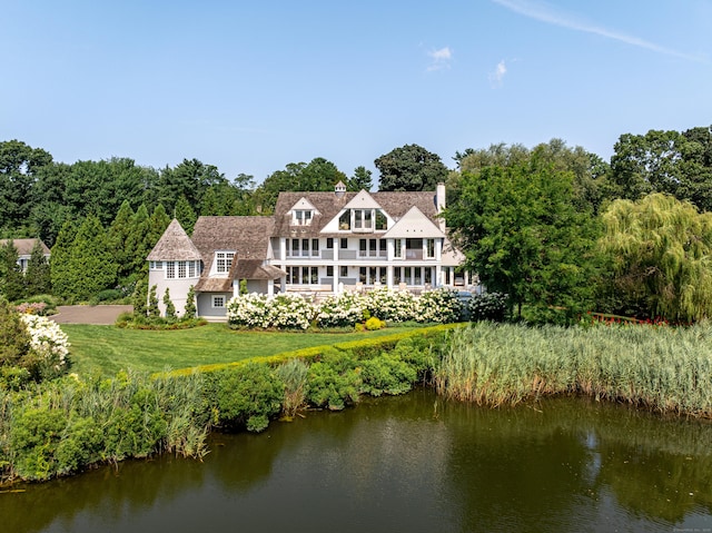 rear view of house with a water view and a yard