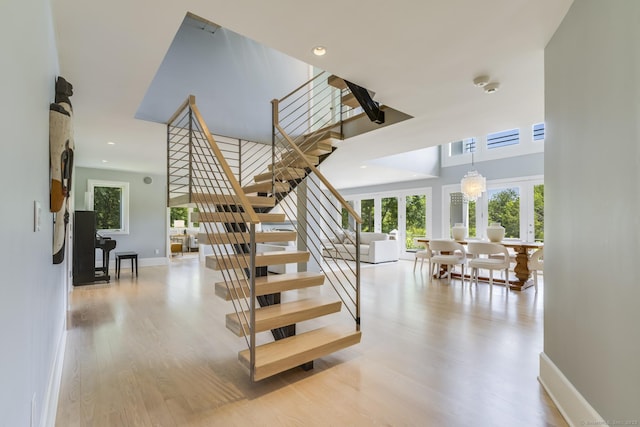 stairway with wood-type flooring and a chandelier