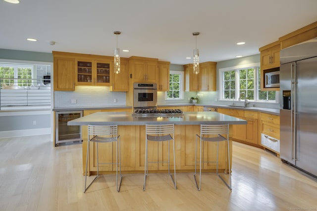 kitchen featuring a kitchen bar, stainless steel appliances, wine cooler, a kitchen island, and pendant lighting