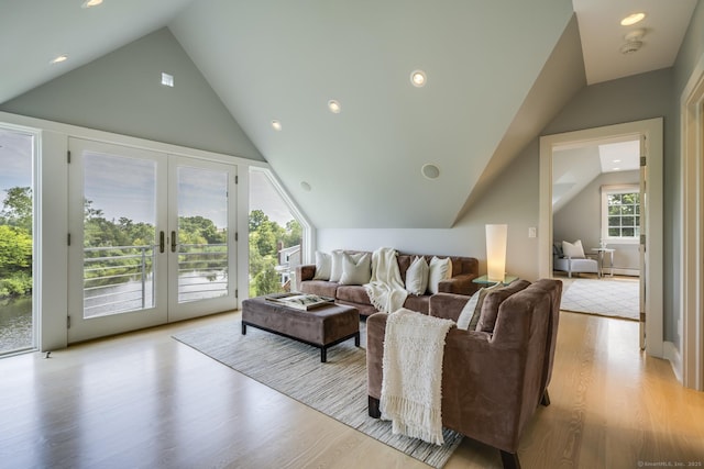 living room with light hardwood / wood-style floors, french doors, and vaulted ceiling