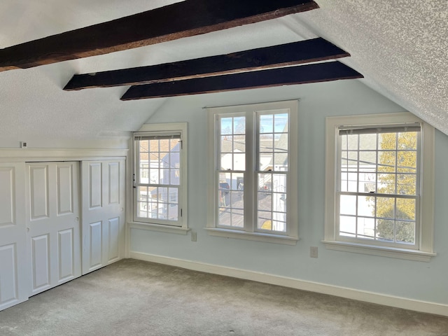 interior space featuring lofted ceiling with beams and a textured ceiling