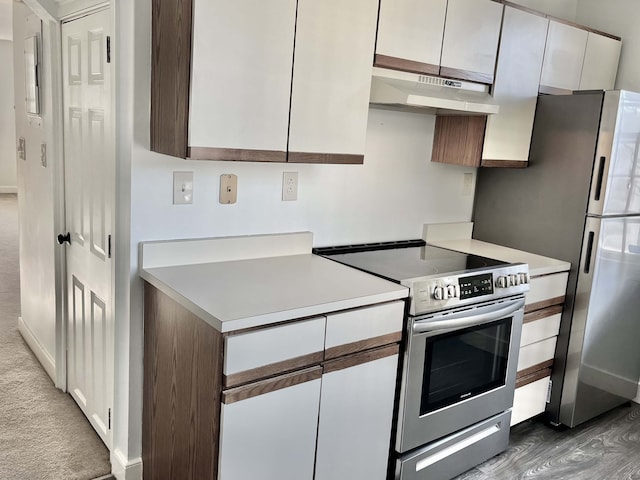 kitchen with white cabinets, appliances with stainless steel finishes, and dark hardwood / wood-style flooring