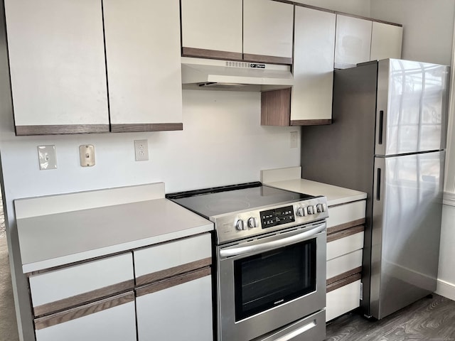 kitchen with dark wood-type flooring, white cabinets, and appliances with stainless steel finishes