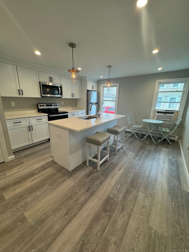 kitchen with stainless steel appliances, dark wood-style floors, white cabinets, and an island with sink