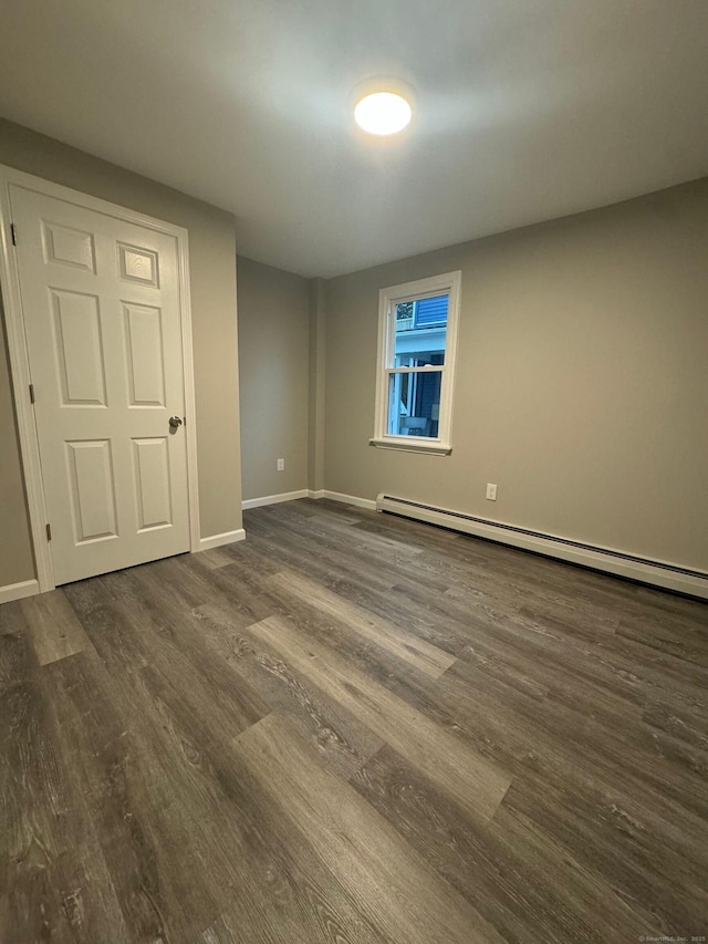 unfurnished room with dark wood-style floors, baseboards, and a baseboard radiator