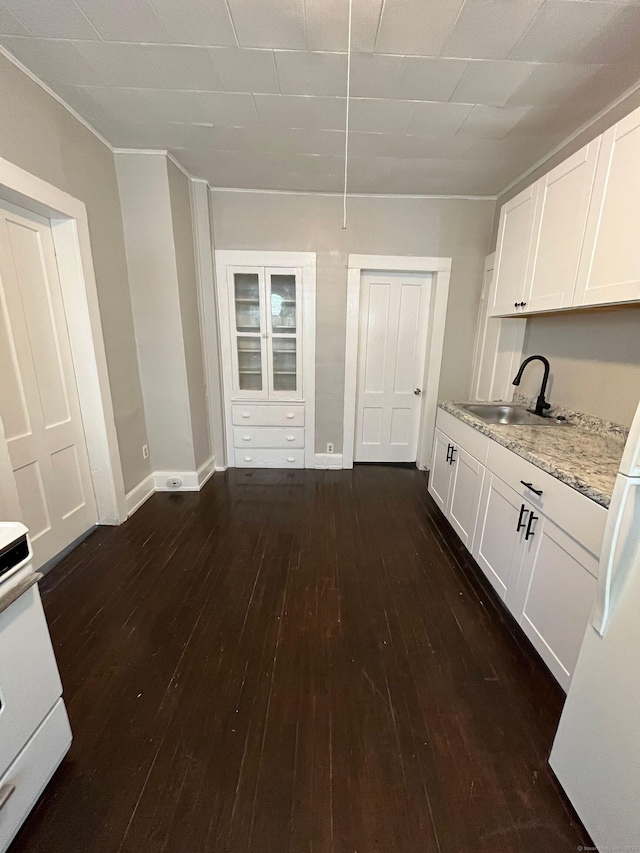 kitchen featuring dark wood finished floors, light stone countertops, white cabinetry, and a sink