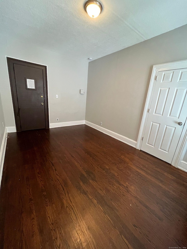 spare room featuring dark wood-style floors, a textured ceiling, and baseboards