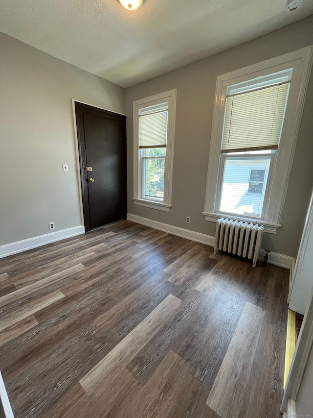 interior space with radiator heating unit, wood finished floors, and baseboards