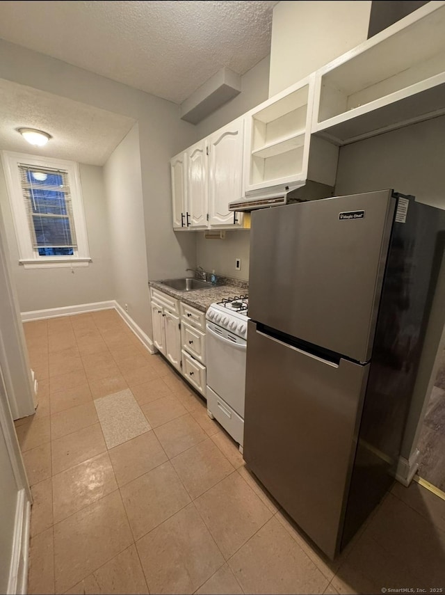 kitchen with a textured ceiling, white range with gas cooktop, white cabinetry, and freestanding refrigerator