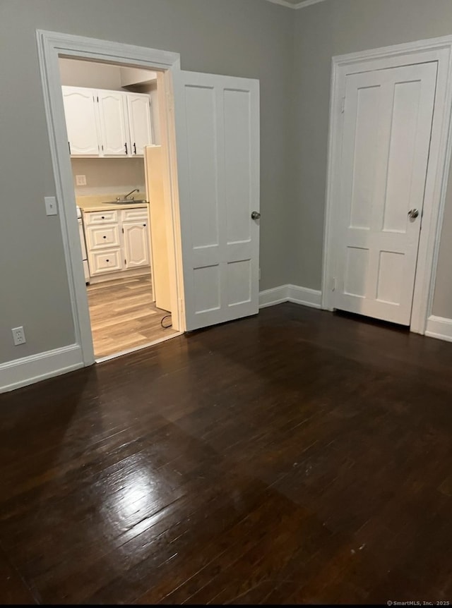 interior space featuring baseboards, dark wood-style flooring, and a sink