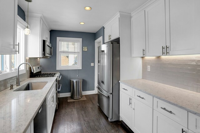 kitchen with white cabinetry, sink, decorative light fixtures, and appliances with stainless steel finishes