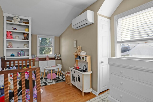 bedroom with lofted ceiling, an AC wall unit, and light wood-type flooring