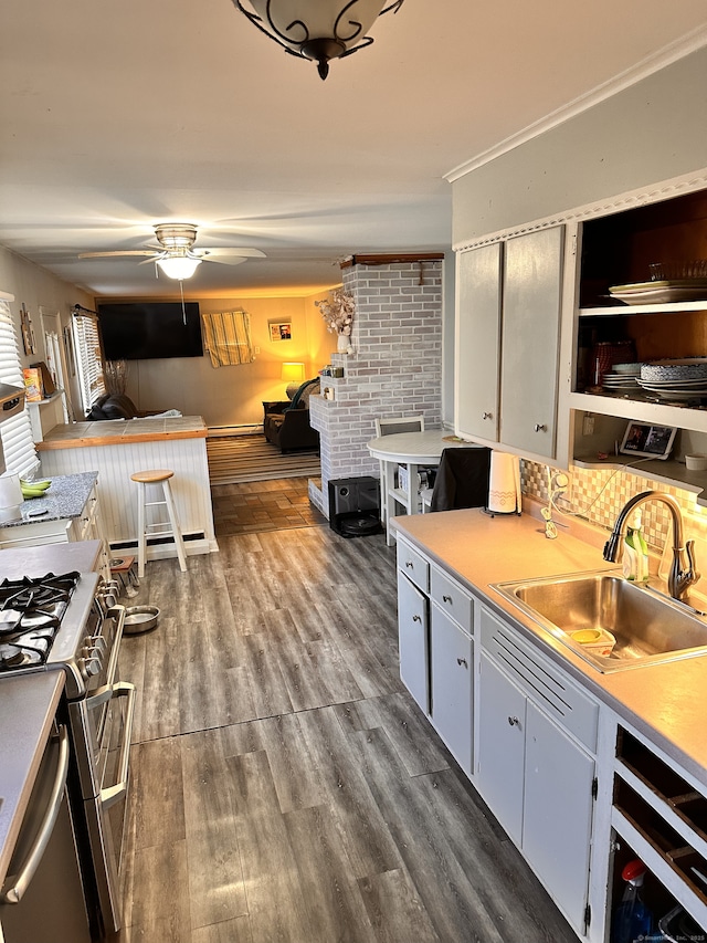 kitchen featuring range with two ovens, sink, dark hardwood / wood-style floors, ceiling fan, and crown molding