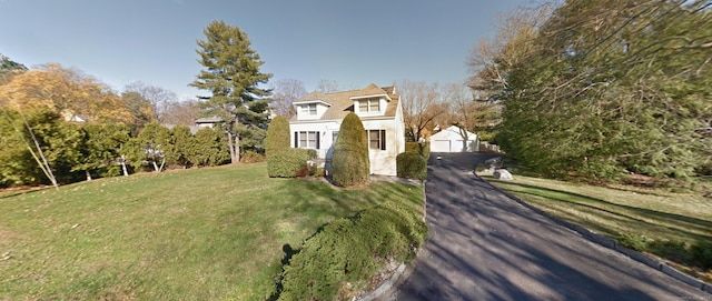 view of front of home with a garage, a front yard, and an outbuilding