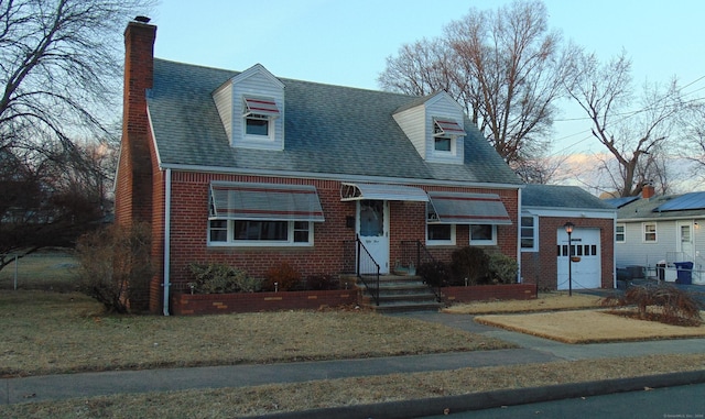 new england style home featuring a garage and a front lawn