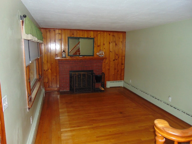 living room featuring a fireplace, wooden walls, light hardwood / wood-style floors, and a baseboard radiator