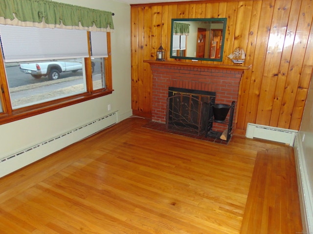 unfurnished living room with baseboard heating, hardwood / wood-style floors, and a fireplace