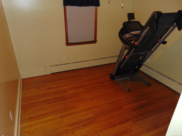 exercise area with hardwood / wood-style floors and a baseboard radiator