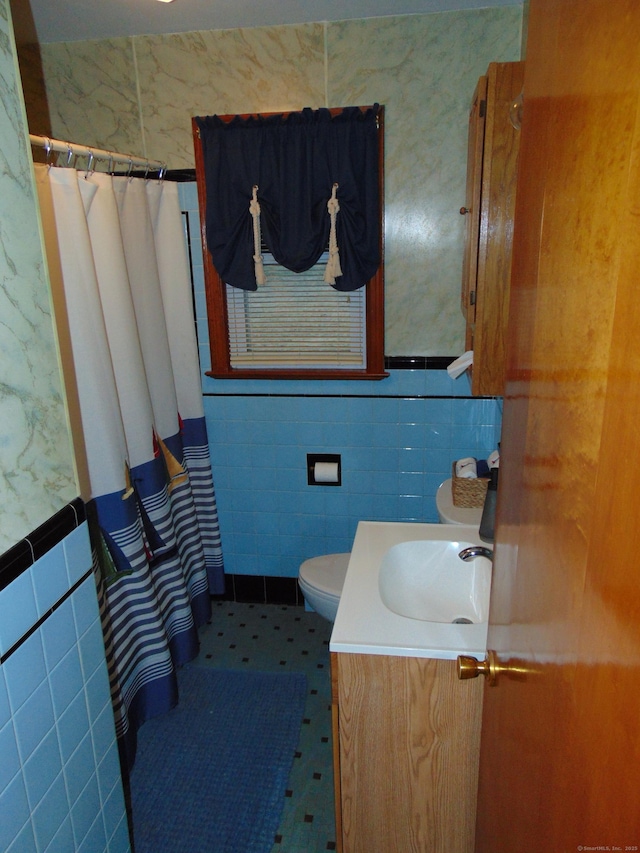 bathroom with toilet, vanity, and tile walls