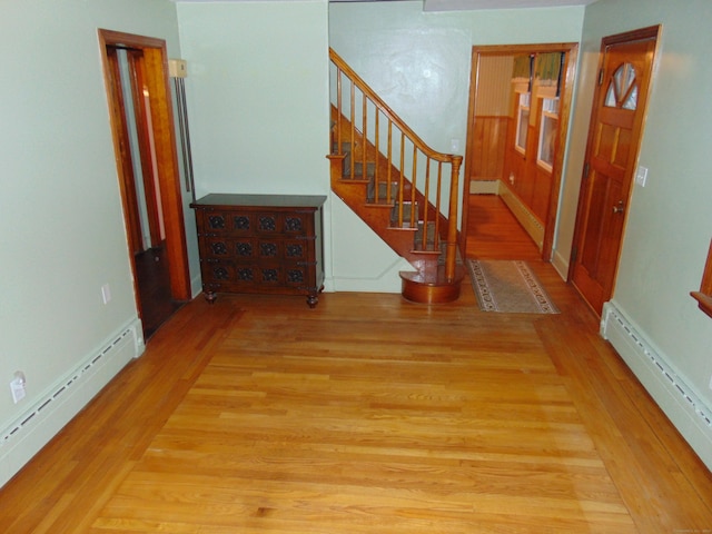 corridor with a baseboard heating unit and light hardwood / wood-style floors