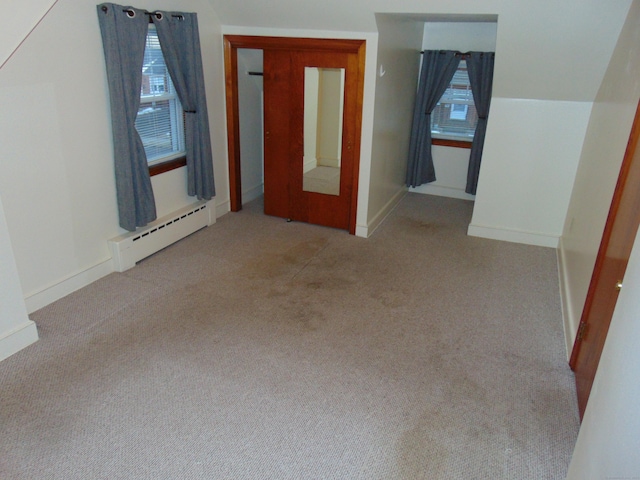 additional living space with light carpet and a baseboard radiator