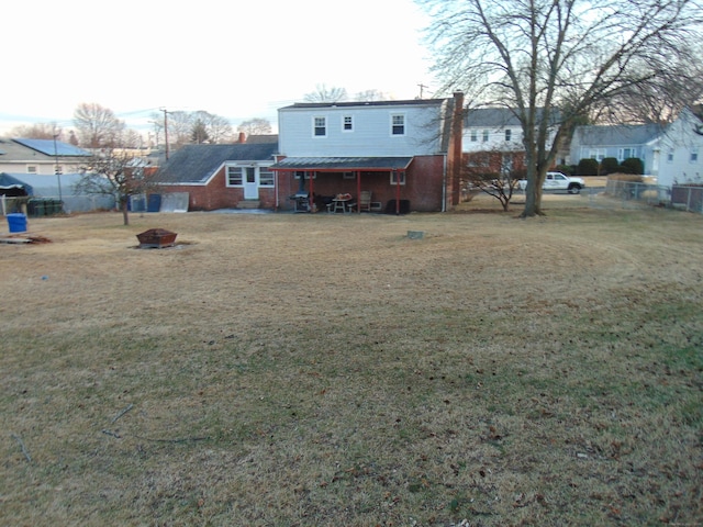 back of house featuring a fire pit and a lawn