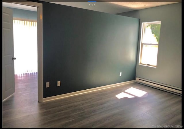 unfurnished room with baseboard heating and dark wood-type flooring