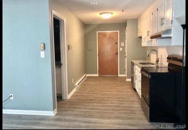 kitchen with black electric range oven, white cabinetry, a baseboard heating unit, light wood-type flooring, and sink