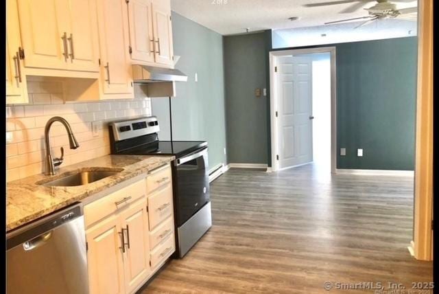 kitchen with light stone countertops, appliances with stainless steel finishes, ceiling fan, sink, and hardwood / wood-style flooring